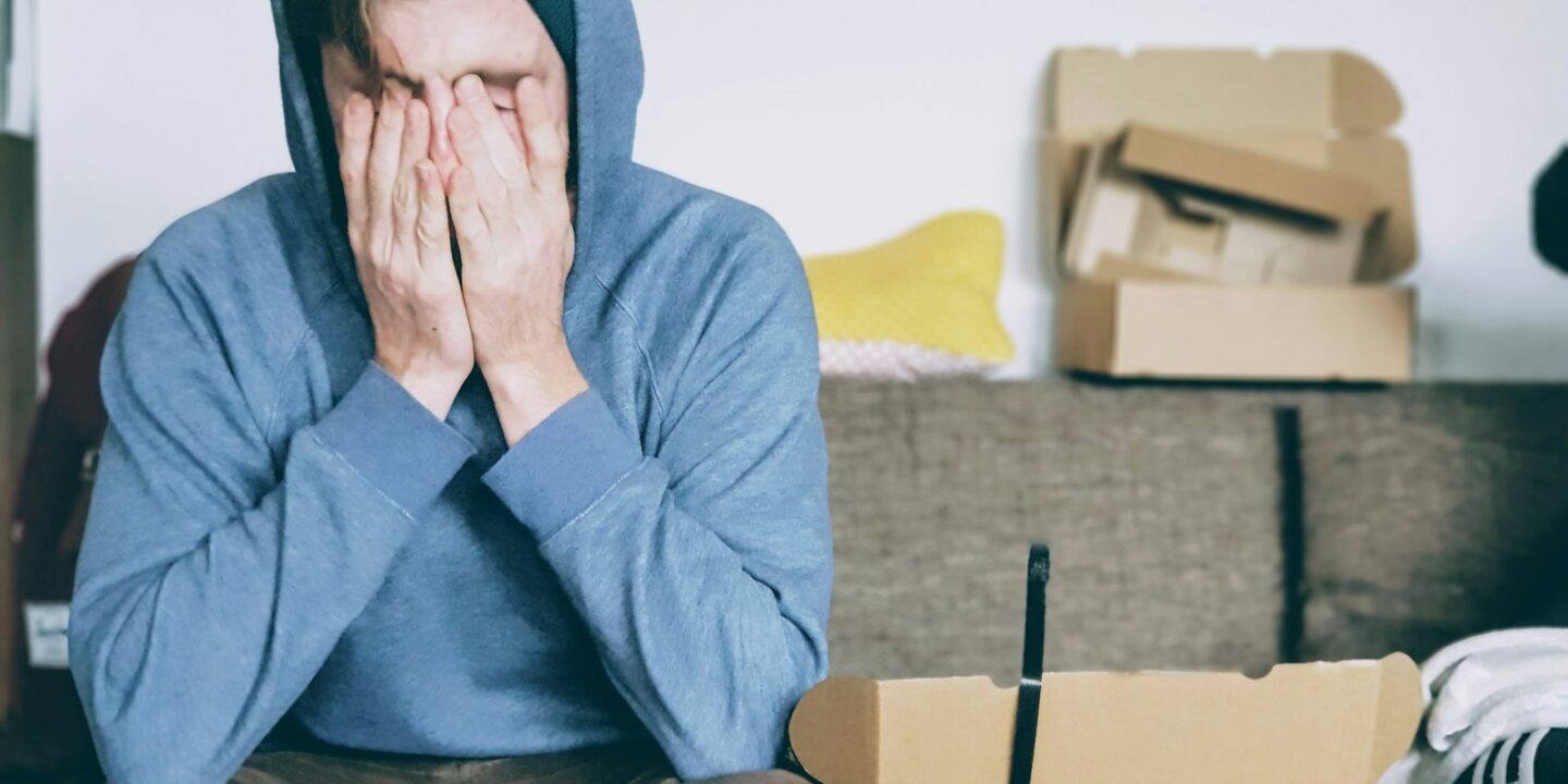 man covering face with both hands while sitting on bench